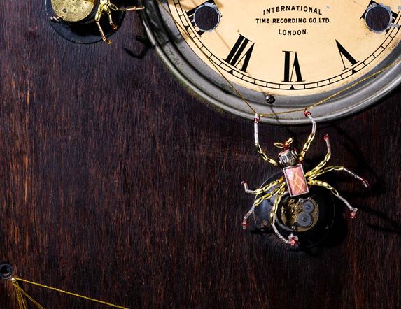 Picture of a old fashioned clock with two spiders on it and a web just below