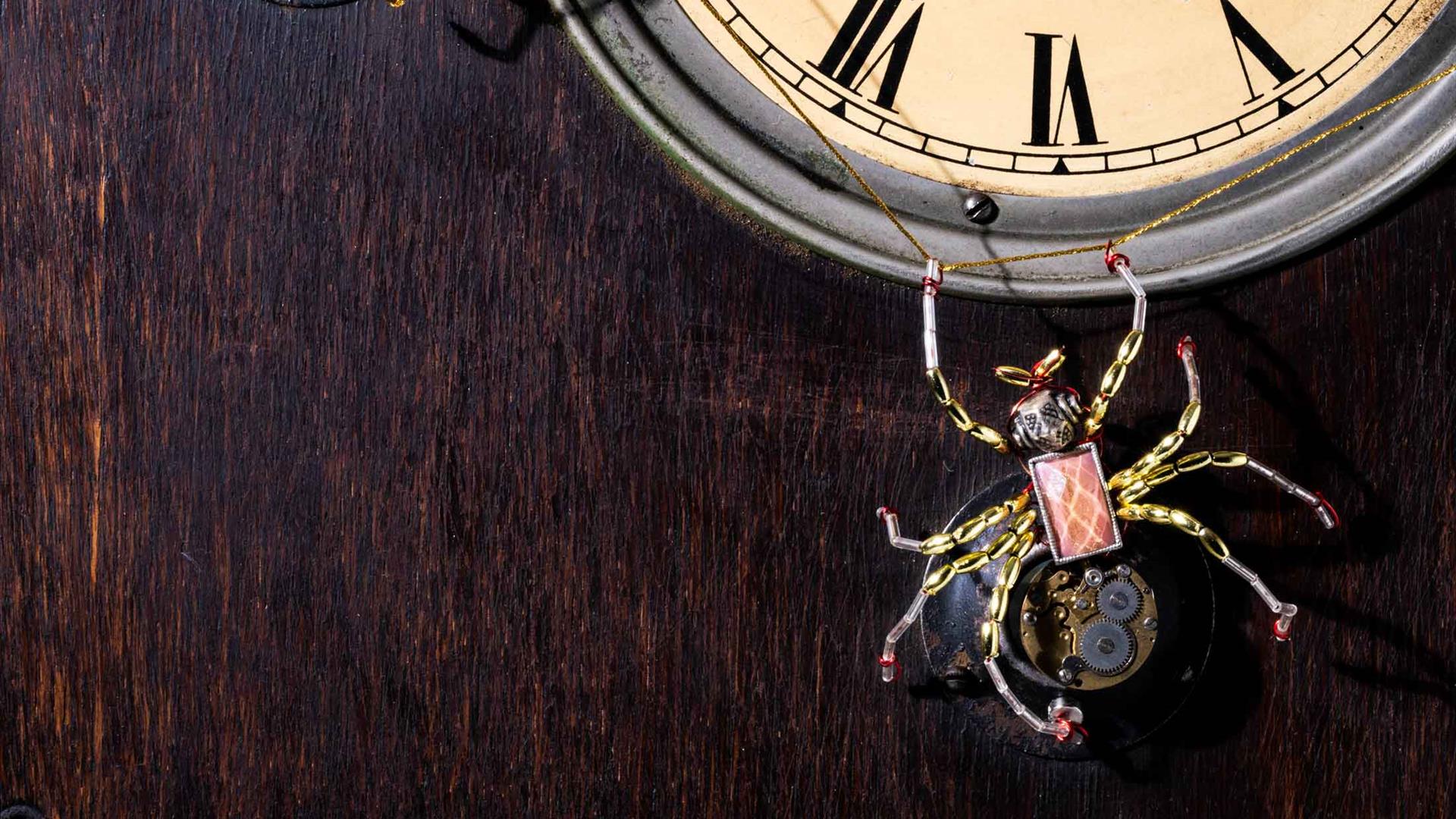Picture of a old fashioned clock with two spiders on it and a web just below