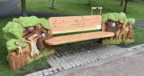 Image shows wooden bench in a park with engraving 'I Love you to the moon and back7