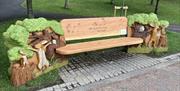 Image shows wooden bench in a park with engraving 'I Love you to the moon and back7