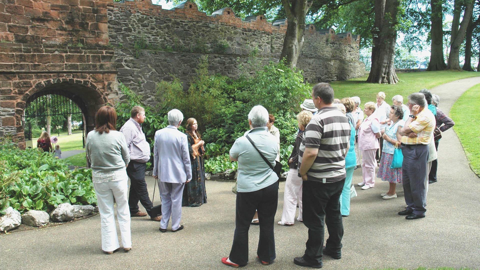 Image is of people on a guided tour of Castle Gardens