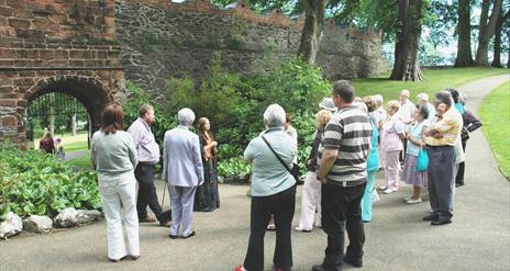 Image is of people on a guided tour of Castle Gardens