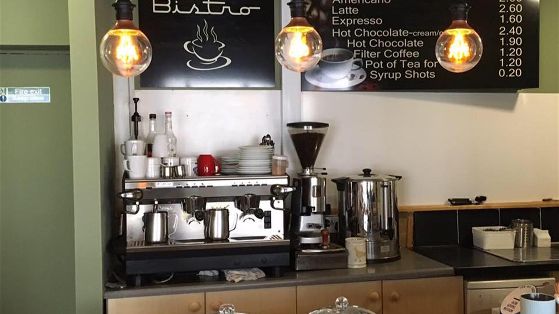 Image shows front counter of Coffee Inc premises with barista machines and traybakes and scones in covered display.
