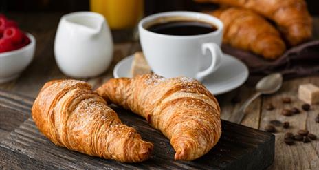 Image shows cup of coffee and two crossiant pasteries.