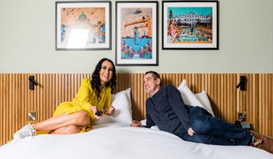 A couple lying on a bed in the Haslem Hotel