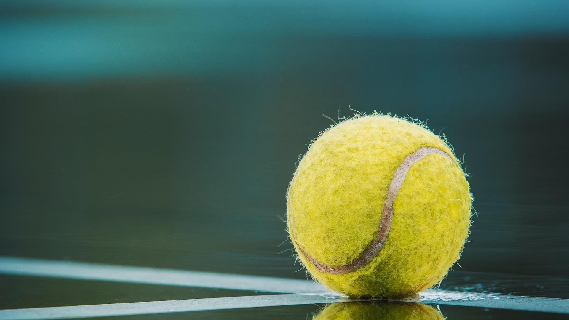 Tennis ball on white line reflected in water with blue background